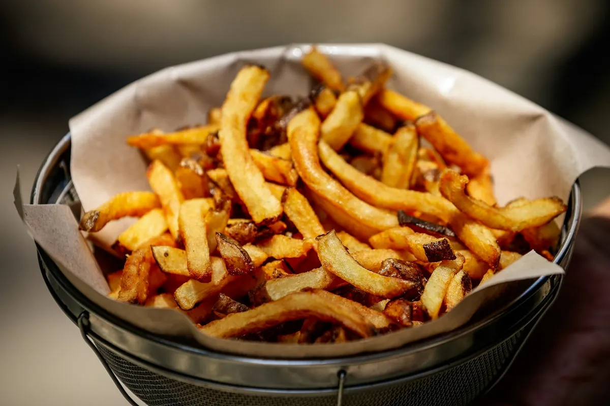 Batatas fritas douradas em tigela, ilustrando o resultado típico de airfryer de gaveta