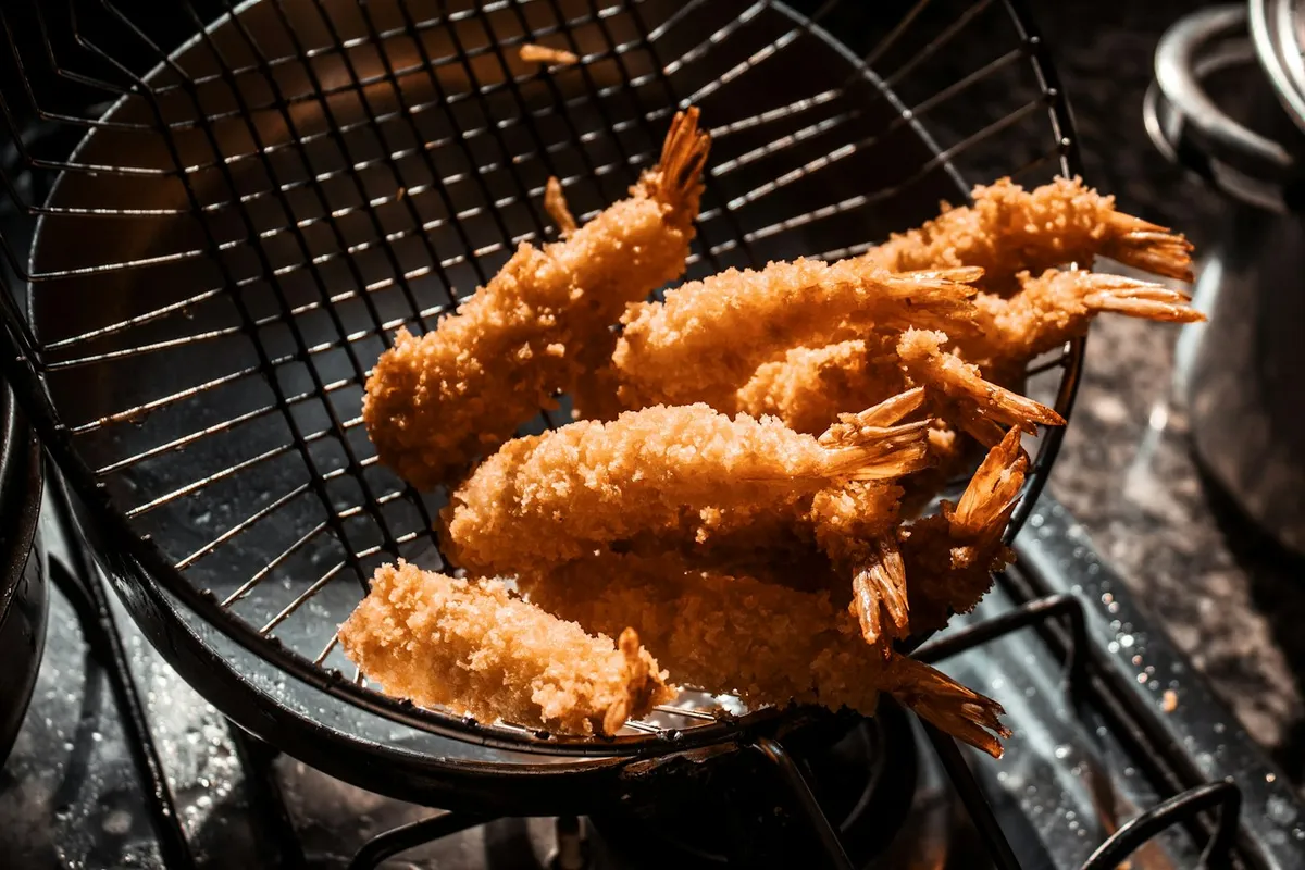 Camarões empanados dourados em cesta de fritura, ilustrando o resultado de uma airfryer