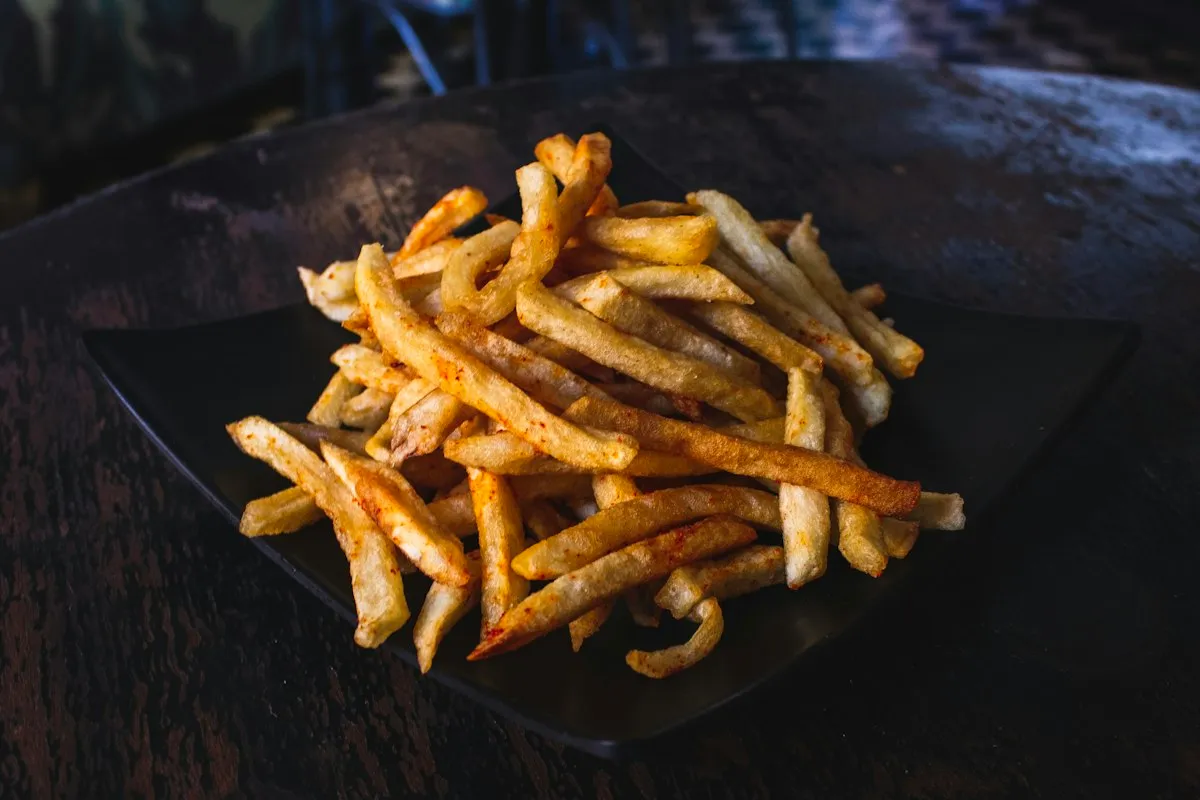 Porção generosa de batatas fritas douradas e crocantes em cesto, ilustrando o preparo típico de alimentos em fritadeira sem óleo