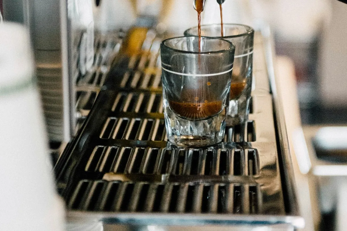 Cafeteira elétrica com jarra de vidro sobre bancada de cozinha preparando café passado fresco