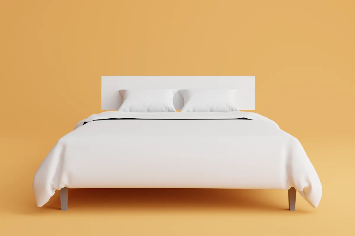 Cama de casal arrumada com edredom e travesseiros brancos em quarto iluminado, ilustrando conforto e suporte de colchões de espuma