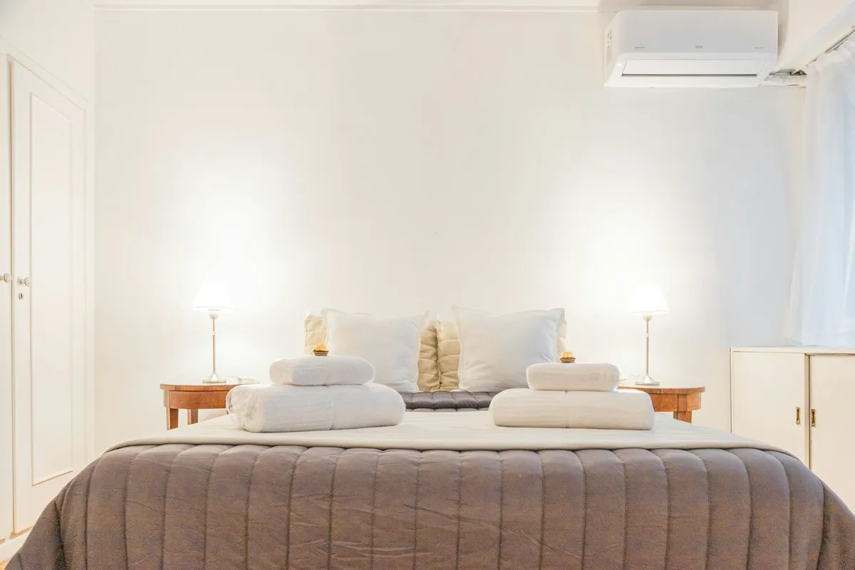 Cama de casal arrumada com lençol branco e travesseiros em quarto moderno, ilustração de categoria