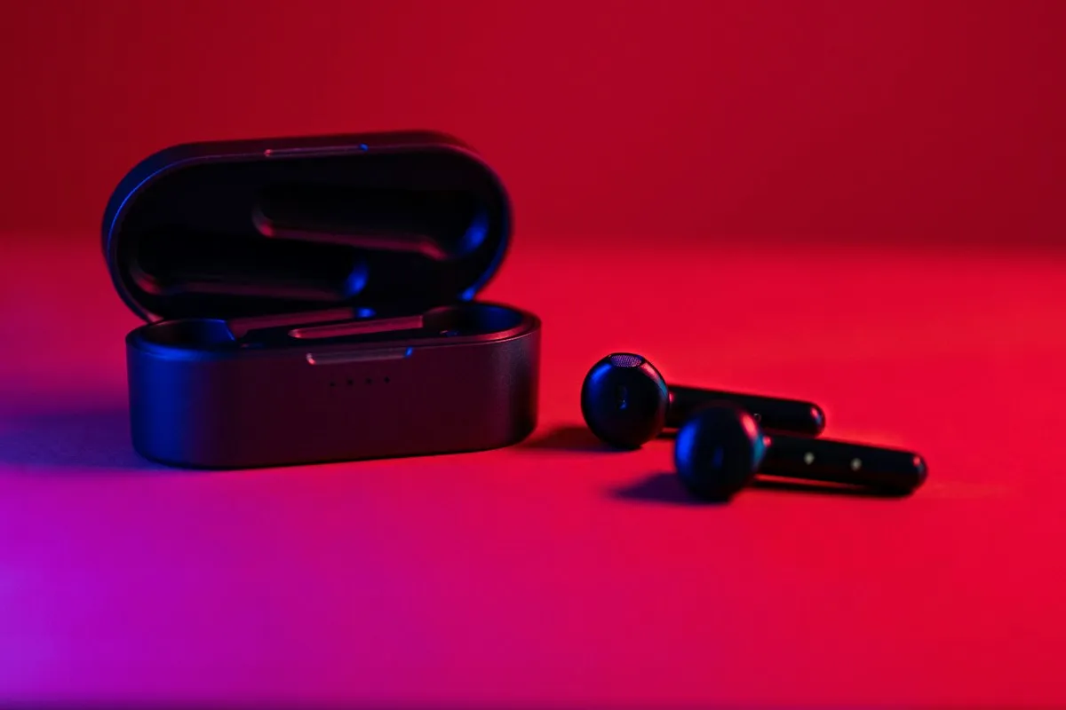 Fones de ouvido sem fio brancos em estojo compacto sobre mesa de trabalho, representando fones TWS