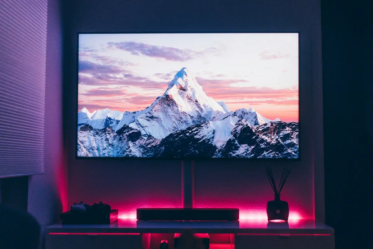 Televisor de tela plana ligado exibindo imagens coloridas em suporte na parede de sala de estar